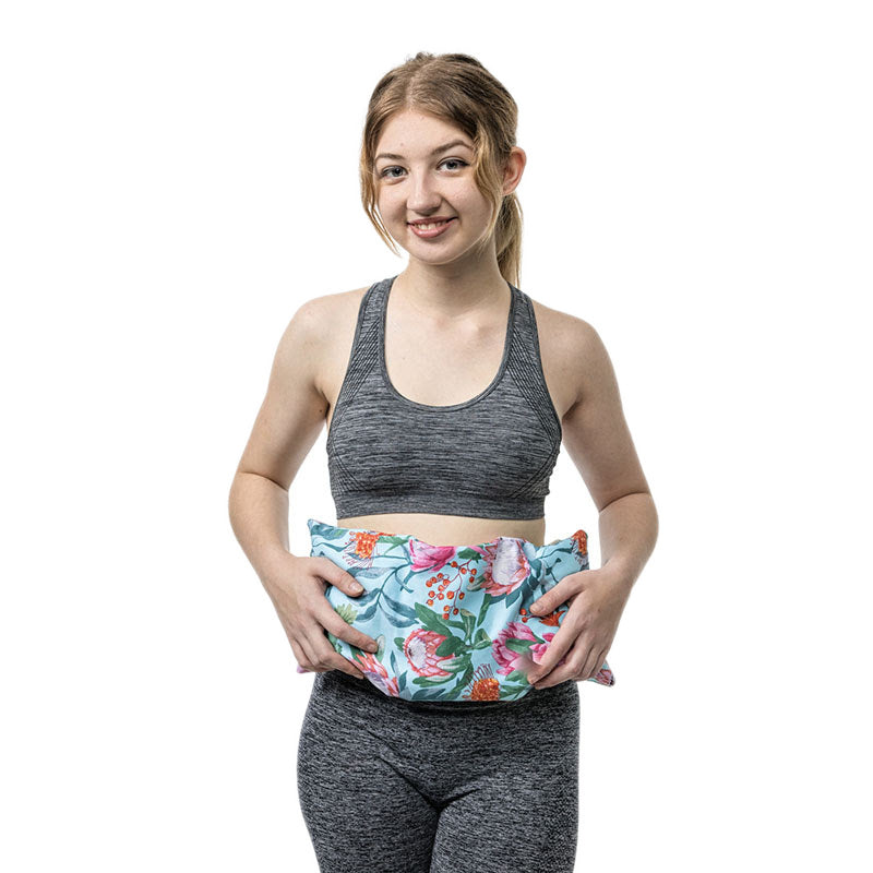 Woman holding the Original heat pack in protea print against her stomach